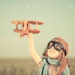 19761824-glückliches-kind-spielt-mit-spielzeug-flugzeug-gegen-blauen-sommerhimmel-hintergrund.jpg